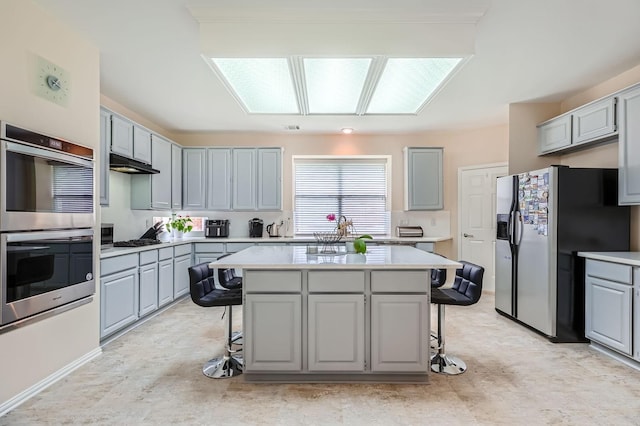 631 Ridgemont Dr, Allen, TX 75002 - kitchen featuring stainless steel appliances, gray cabinetry, a kitchen bar, and light countertops