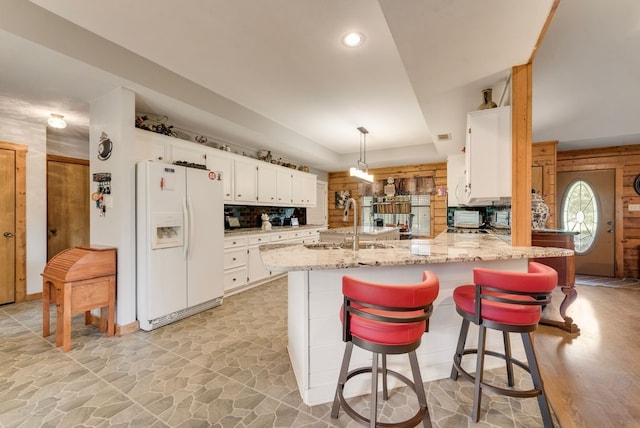 14213 Clark Dr, Streetman, TX 75859 - kitchen featuring white fridge with ice dispenser, a peninsula, white cabinets, stone floors, and light stone counters