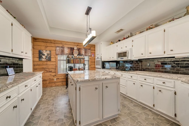 14213 Clark Dr, Streetman, TX 75859 - kitchen with white appliances, decorative backsplash, white cabinetry, and wooden walls