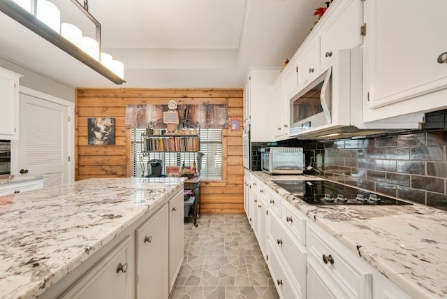 14213 Clark Dr, Streetman, TX 75859 - kitchen with white cabinetry, backsplash, black electric cooktop, wooden walls, and light stone counters