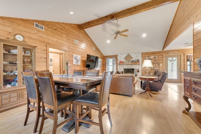 14213 Clark Dr, Streetman, TX 75859 - dining area featuring wood walls, a ceiling fan, a stone fireplace, light wood finished floors, and beam ceiling