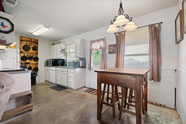 1105 Ashwood Ct, Cleburne, TX 76033 - kitchen featuring concrete floors, hanging light fixtures, white cabinetry, stainless steel microwave, and dishwasher