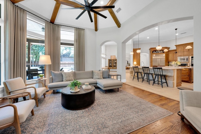4340 Powers Branch Dr, Midlothian, TX 76065 - living area featuring arched walkways, a ceiling fan, light wood-style flooring, beam ceiling, and high vaulted ceiling