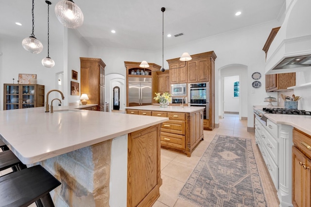 4340 Powers Branch Dr, Midlothian, TX 76065 - kitchen featuring custom exhaust hood, built in appliances, arched walkways, an island with sink, and a kitchen bar