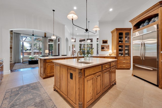 4340 Powers Branch Dr, Midlothian, TX 76065 - kitchen featuring built in fridge, arched walkways, a center island with sink, ceiling fan, and brown cabinets