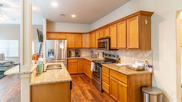 2231 Cobblestone Ct, Granbury, TX 76049 - kitchen with stainless steel appliances, wood finished floors, backsplash, light stone counters, and recessed lighting