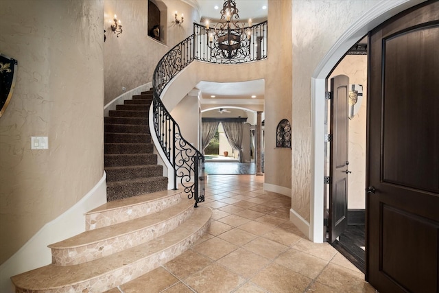 1608 Rivercrest Ct, Fort Worth, TX 76107 - foyer featuring arched walkways, a textured wall, a towering ceiling, stairs, and a chandelier