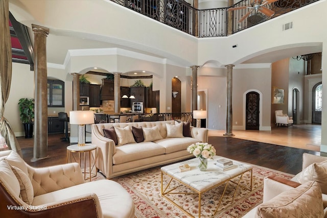 1608 Rivercrest Ct, Fort Worth, TX 76107 - living room with decorative columns, wood finished floors, a towering ceiling, arched walkways, and baseboards