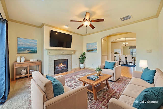 1891 Signal Ridge Pl, Rockwall, TX 75032 - living area with arched walkways, ceiling fan, crown molding, wood finished floors, and a tiled fireplace
