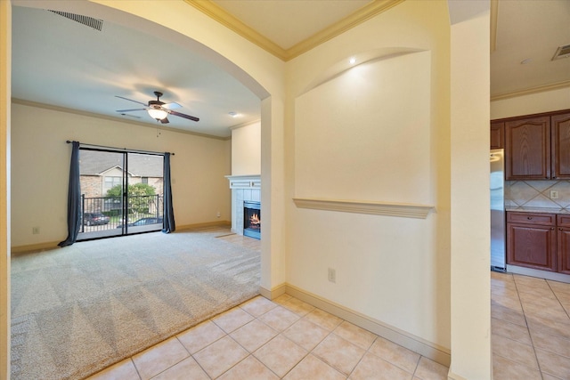 1891 Signal Ridge Pl, Rockwall, TX 75032 - unfurnished living room with crown molding, ceiling fan, light tile patterned floors, a fireplace, and arched walkways