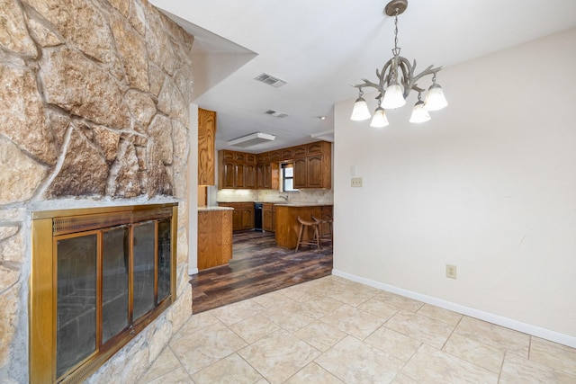 2126 Los Robles St, Grapevine, TX 76051 - kitchen with brown cabinetry, light countertops, a chandelier, a sink, and baseboards