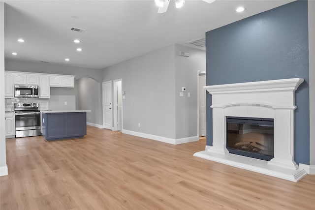 10833 Hawks Landing Rd, Fort Worth, TX 76052 - unfurnished living room featuring arched walkways, light wood-type flooring, baseboards, a ceiling fan, and recessed lighting
