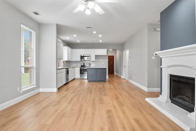 10833 Hawks Landing Rd, Fort Worth, TX 76052 - kitchen featuring appliances with stainless steel finishes, ceiling fan, decorative backsplash, light wood-type flooring, and arched walkways