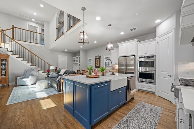 232 Skystone Dr, Irving, TX 75038 - kitchen with blue cabinets, stainless steel appliances, open floor plan, white cabinets, and light countertops