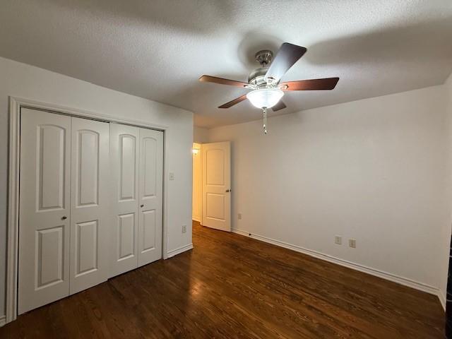511 W Bonham Ave, Cooper, TX 75432 - unfurnished bedroom with dark wood-type flooring, baseboards, a closet, a ceiling fan, and a textured ceiling