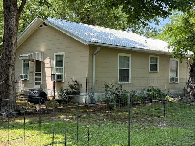511 W Bonham Ave, Cooper, TX 75432 - view of property exterior featuring metal roof and cooling unit