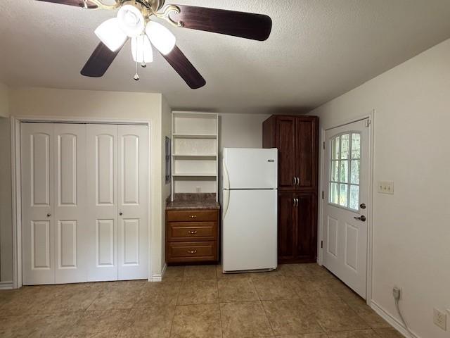 511 W Bonham Ave, Cooper, TX 75432 - kitchen featuring freestanding refrigerator, open shelves, a ceiling fan, light tile patterned floors, and baseboards