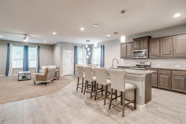817 Nicole Way, Fort Worth, TX 76028 - kitchen with stainless steel appliances, light wood-style flooring, a breakfast bar area, open floor plan, and a center island with sink