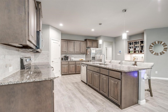 817 Nicole Way, Fort Worth, TX 76028 - kitchen featuring stainless steel appliances, a sink, light wood-style floors, decorative backsplash, and a breakfast bar area
