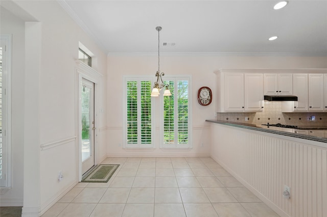 2004 Kodiak Ct, Arlington, TX 76013 - kitchen with under cabinet range hood, dark countertops, light tile patterned floors, pendant lighting, and white cabinets