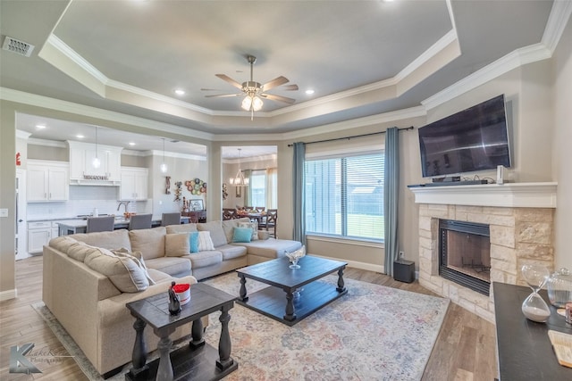 357 Blue Lake Dr, Abilene, TX 79602 - living area with a tray ceiling, ceiling fan, crown molding, a stone fireplace, and light wood-style floors
