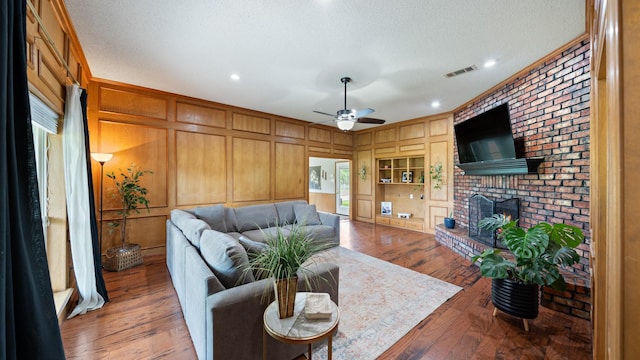 5691 Priscilla Ln, Kaufman, TX 75142 - living room with ceiling fan, a fireplace, wood finished floors, wood walls, and a textured ceiling