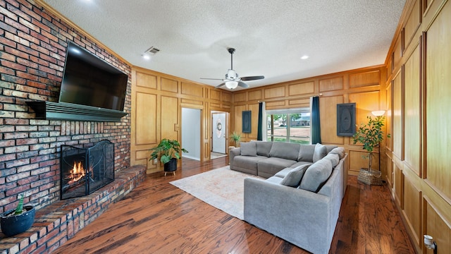 5691 Priscilla Ln, Kaufman, TX 75142 - living room with a decorative wall, a fireplace, a textured ceiling, a ceiling fan, and wood finished floors