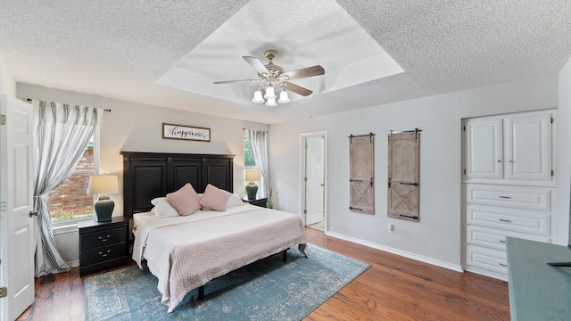 5691 Priscilla Ln, Kaufman, TX 75142 - bedroom with a textured ceiling, wood finished floors, baseboards, a tray ceiling, and ceiling fan