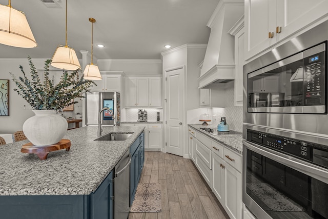 381 Oak Meadow Ln, Weatherford, TX 76085 - kitchen with a sink, stainless steel appliances, blue cabinets, custom range hood, and white cabinetry