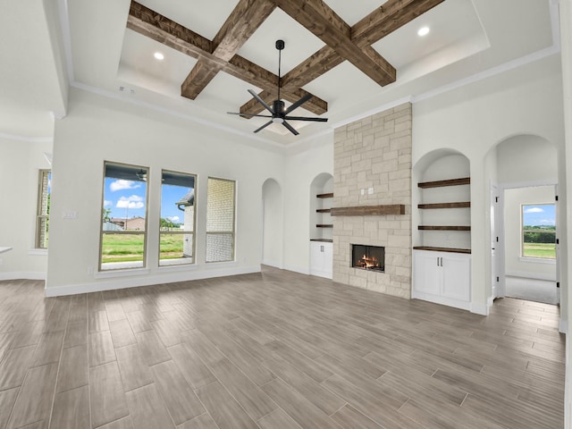 161 Altom Rd, Springtown, TX 76082 - unfurnished living room featuring a ceiling fan, arched walkways, a stone fireplace, coffered ceiling, and beam ceiling