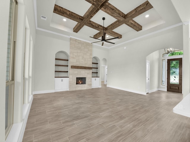 161 Altom Rd, Springtown, TX 76082 - unfurnished living room featuring arched walkways, coffered ceiling, ceiling fan, beamed ceiling, and a stone fireplace