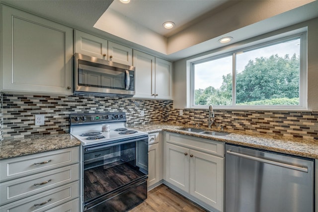 2315 Yale Dr, Arlington, TX 76015 - kitchen featuring appliances with stainless steel finishes, a sink, light wood-type flooring, tasteful backsplash, and light stone counters