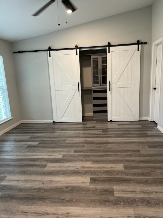 1605 Baltimore Dr, Richardson, TX 75081 - unfurnished bedroom featuring a barn door, baseboards, and dark wood-type flooring