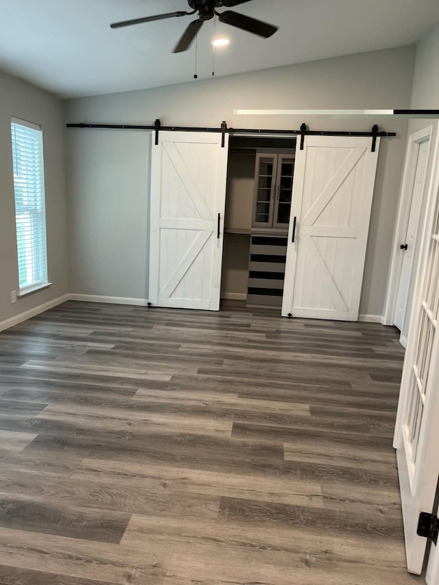 1605 Baltimore Dr, Richardson, TX 75081 - unfurnished bedroom featuring a barn door, baseboards, vaulted ceiling, and dark wood-style flooring