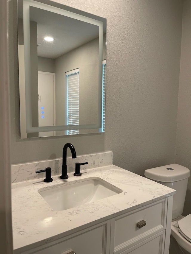 1605 Baltimore Dr, Richardson, TX 75081 - half bath with vanity, toilet, and a textured wall