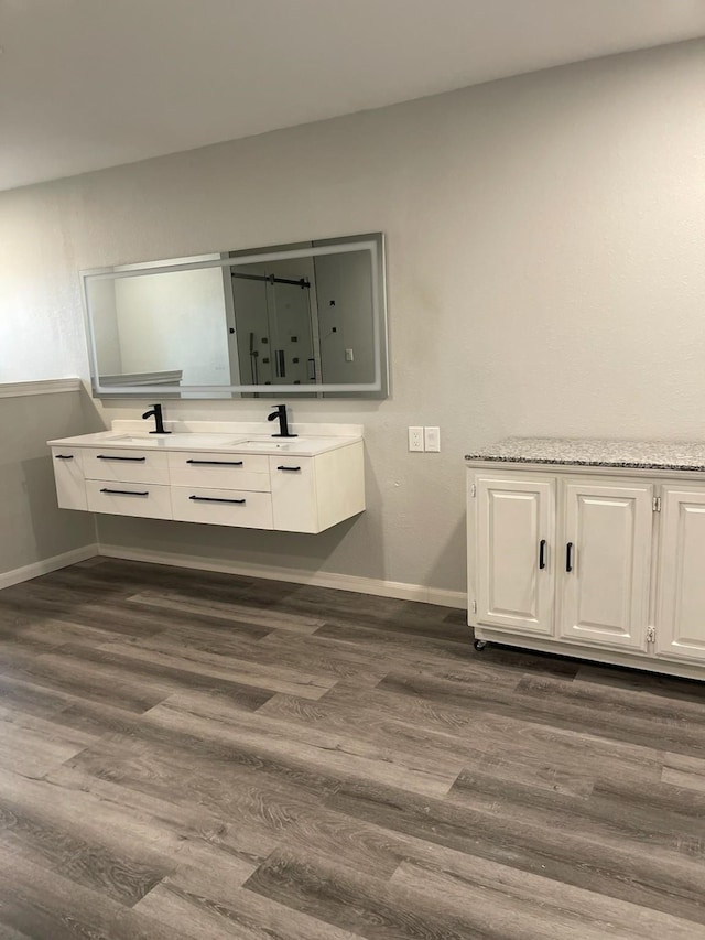 1605 Baltimore Dr, Richardson, TX 75081 - bathroom with double vanity, wood finished floors, and baseboards