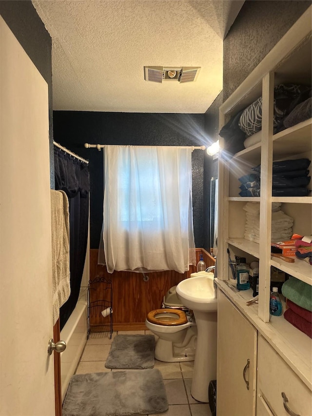 567 N Rice, Hamilton, TX 76531 - bathroom featuring tile patterned floors, toilet, a textured ceiling, and shower / tub combo with curtain