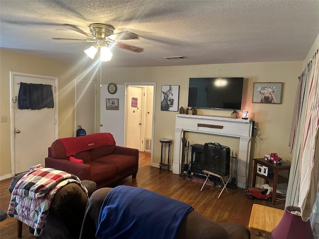 567 N Rice, Hamilton, TX 76531 - living room featuring wood finished floors, a ceiling fan, a textured ceiling, and a wood stove