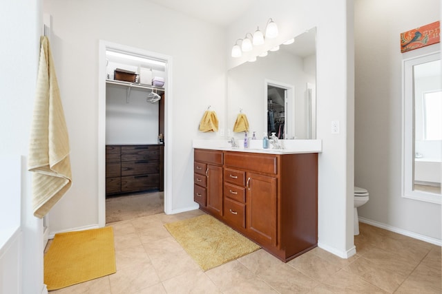 3216 Jackal Dr, Lorena, TX 76655 - bathroom featuring double vanity, a walk in closet, toilet, baseboards, and tile patterned flooring