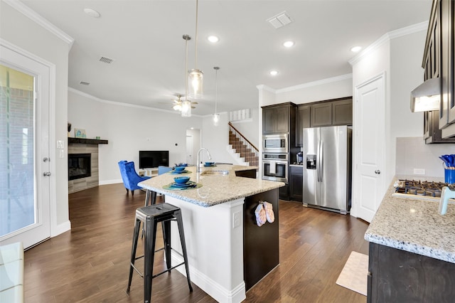 7216 Monet Ln, Grand Prairie, TX 75054 - kitchen with stainless steel appliances, a sink, a tiled fireplace, dark brown cabinetry, and open floor plan