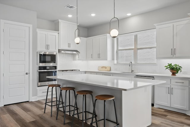 1302 20th St, Northlake, TX 76226 - kitchen featuring stainless steel appliances, a breakfast bar area, a center island, under cabinet range hood, and dark wood-style flooring