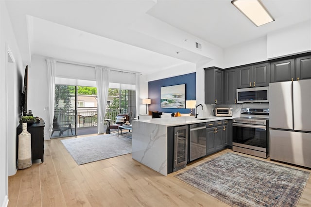 3225 Turtle Creek Blvd Unit 330, Dallas, TX 75219 - kitchen featuring stainless steel appliances, a sink, a peninsula, and light wood finished floors