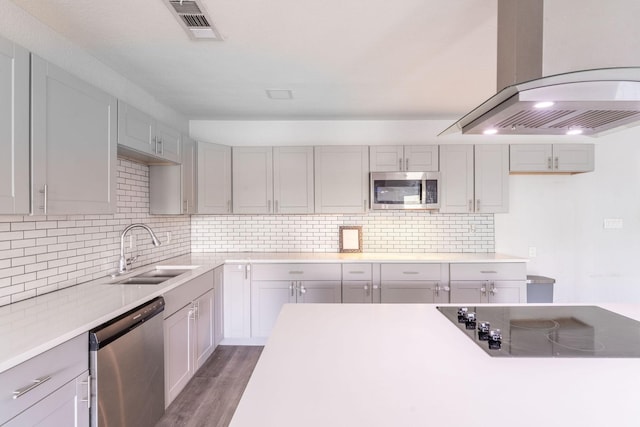 2835 Gladstone Dr, Dallas, TX 75211 - kitchen featuring stainless steel appliances, a sink, wall chimney range hood, decorative backsplash, and wood finished floors