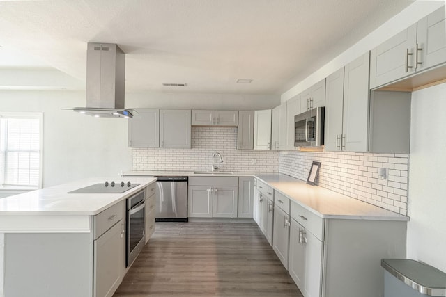 2835 Gladstone Dr, Dallas, TX 75211 - kitchen with stainless steel appliances, island exhaust hood, a sink, wood finished floors, and tasteful backsplash