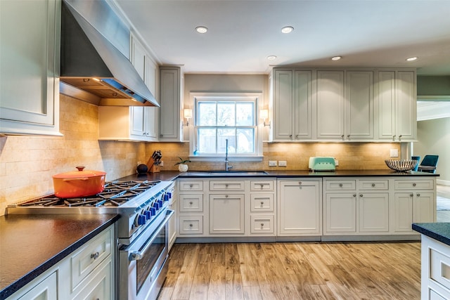 3241 Merrell Cir, Dallas, TX 75229 - kitchen featuring wall chimney range hood, high end stainless steel range oven, a sink, dark countertops, and light wood-style flooring