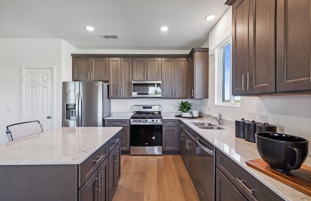 1041 Clear Dusk Ln, Forney, TX 75126 - kitchen with stainless steel appliances, a sink, dark brown cabinetry, a center island, and light stone countertops