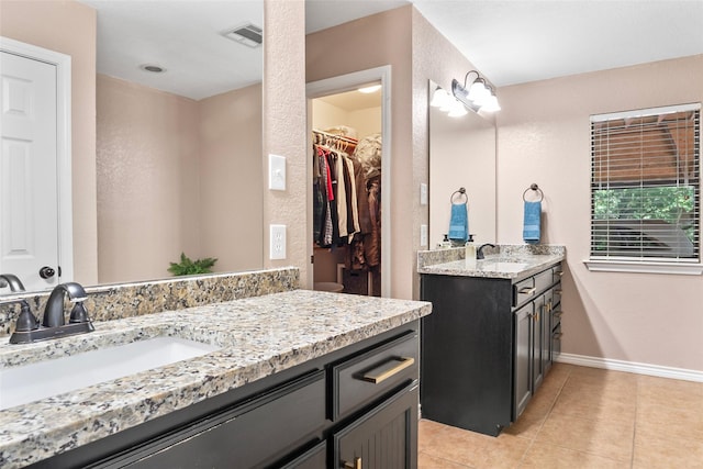 483 County Road 1591, Sunset, TX 76270 - full bathroom featuring two vanities, tile patterned floors, a textured wall, baseboards, and a walk in closet