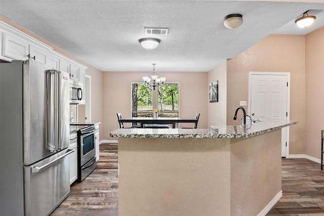 483 County Road 1591, Sunset, TX 76270 - kitchen featuring appliances with stainless steel finishes, an island with sink, dark wood-style flooring, white cabinetry, and a chandelier