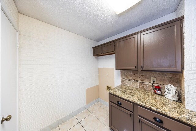 6900 Tudor Dr, Plano, TX 75023 - kitchen with backsplash, light stone countertops, light tile patterned floors, a textured ceiling, and dark brown cabinetry