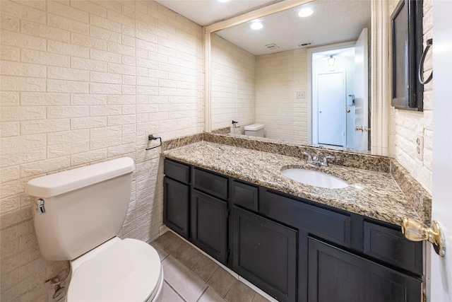 6900 Tudor Dr, Plano, TX 75023 - bathroom featuring toilet, vanity, tile patterned floors, recessed lighting, and tile walls